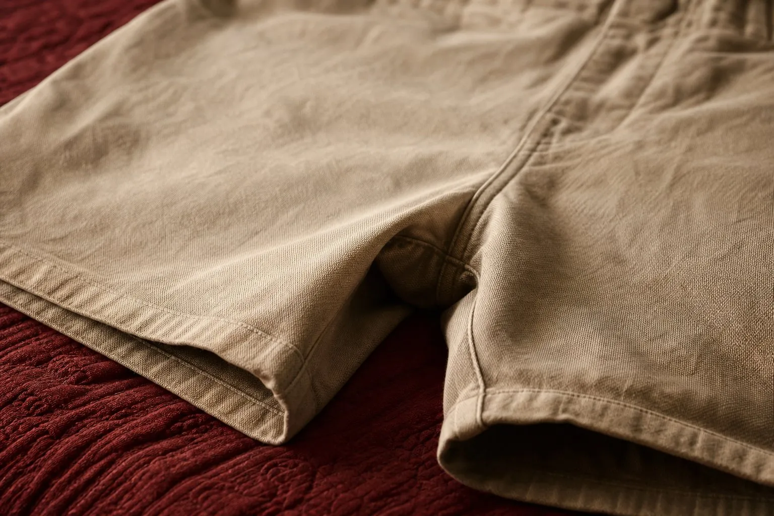 Short en coton beige pose a plat sur un lit, entrejambe et couture interieure en gros plan